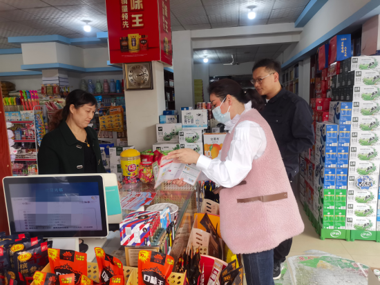 图为德安县烟草专卖局志愿者正在向商铺老板宣传宪法知识